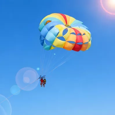 Activité de parachute ascensionnel multicolore dans le ciel bleu azur au-dessus de la mer à Djerba.