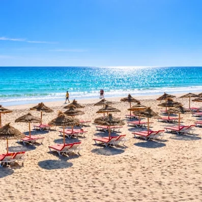 Plage de sable fin, eaux turquoise et parasols en paille typiques de l'hôtel Les Quatre Saisons.