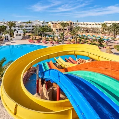 Grand parc aquatique avec toboggans colorés et piscine extérieure sous le soleil de l'hôtel à Djerba.