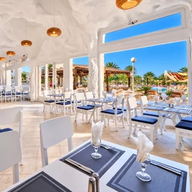 Salle de restaurant lumineuse au design troglodyte avec mobilier blanc moderne à l'hôtel Les Quatre Saisons.