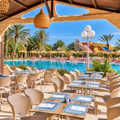 Terrasse ombragée du restaurant offrant une vue imprenable sur la piscine et les toboggans du parc aquatique.