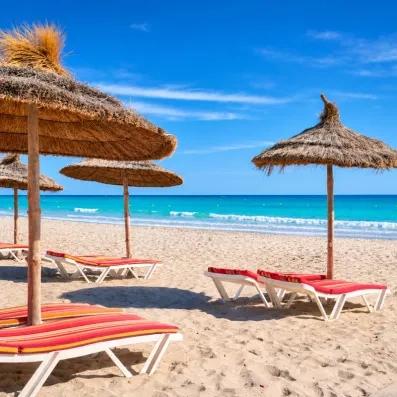 Plage de sable fin, eaux turquoise et parasols en paille typiques de l'hôtel Les Quatre Saisons.
