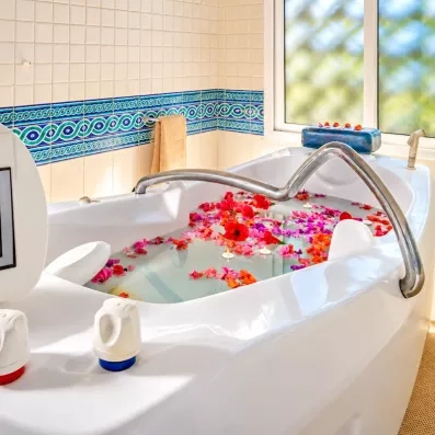 Bain bouillonnant relaxant parsemé de fleurs et bougies au spa de l'hôtel Les Quatre Saisons Djerba.