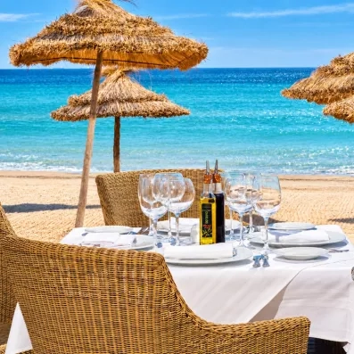Table dressée face à la mer sous des parasols en paille au Royal Thalassa Monastir, Tunisie.