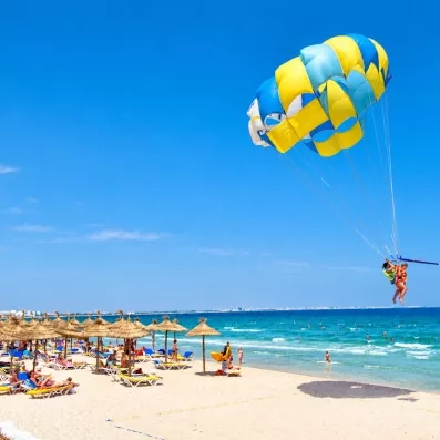 Session de parachute ascensionnel au-dessus de la plage ensoleillée de l’hôtel Royal Thalassa à Monastir.
