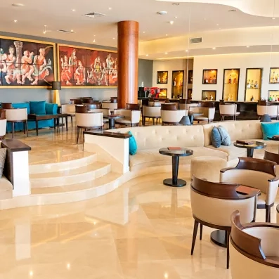 Bar lounge moderne avec fauteuils confortables et fresques artistiques murales au Royal Thalassa Monastir.