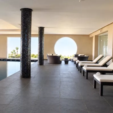 Espace de relaxation design avec transats et colonnes mosaïques face à la piscine au Royal Thalassa Monastir.