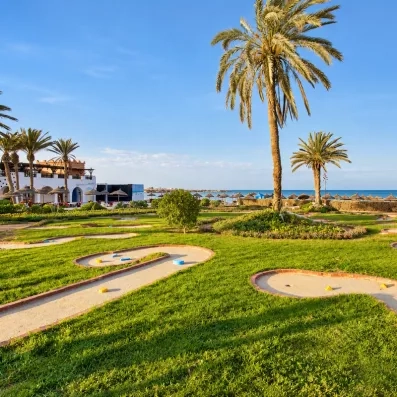 Parcours de mini-golf verdoyant avec palmiers en bord de mer à l'hôtel Safira Palms Djerba.