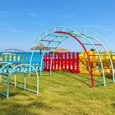 Aire de jeux extérieure pour enfants avec structures colorées et vue sur mer à Djerba.