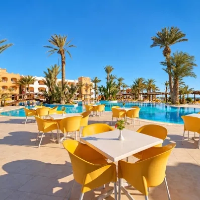 Terrasse ensoleillée avec tables et chaises jaunes face à la piscine de l'hôtel Safira Palms à Djerba.