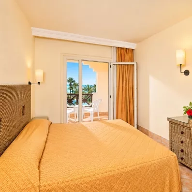 Chambre double confortable avec mobilier en rotin et balcon privé offrant une vue sur mer à Djerba.