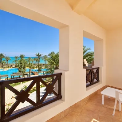 Vue panoramique depuis le balcon d'une chambre sur la piscine, les jardins et la plage de Djerba.