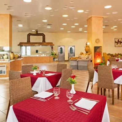 Restaurant buffet spacieux avec tables dressées et chaises en osier à l'hôtel Safira Palms à Djerba.