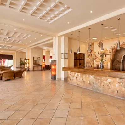 Réception de l'hôtel Safira Palms à Djerba avec un comptoir en bois et une fresque murale traditionnelle.