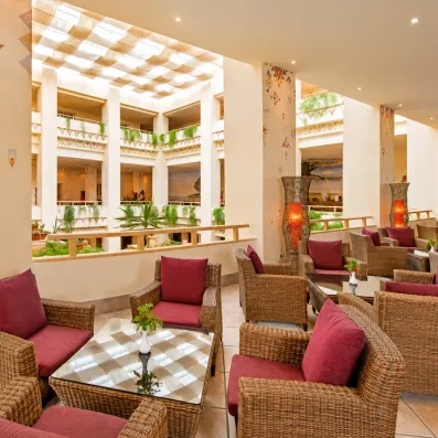 Salon intérieur lumineux avec fauteuils en osier et puits de lumière à l'hôtel Safira Palms de Djerba.