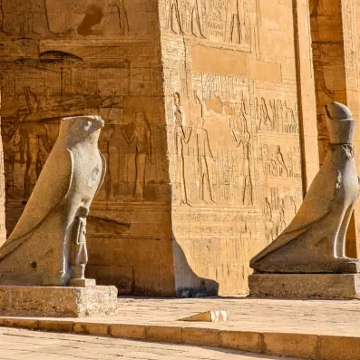 Statue du dieu faucon Horus devant des murs couverts de hiéroglyphes, temple d'Edfou, croisière Égypte.