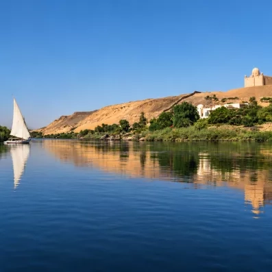Felouque naviguant sur le Nil au coucher du soleil, paysage serein, croisière Secrets des Pharaons, Égypte.