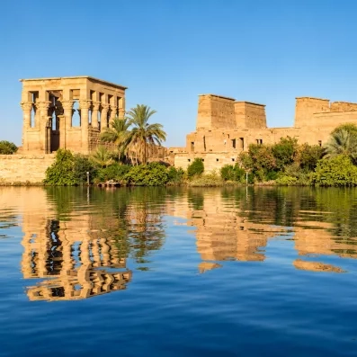 Temple de Philae et kiosque de Trajan reflétés dans les eaux du Nil au bord de la rive à Assouan.