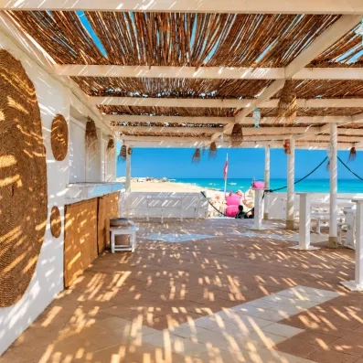 Terrasse ombragée du club de plage privé au César Thalasso Djerba offrant une vue imprenable sur la Méditerranée.
