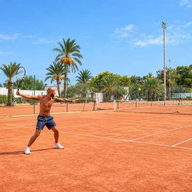 Un court en terre battue entouré de palmiers, pour s'adonner au tennis dans un cadre agréable.