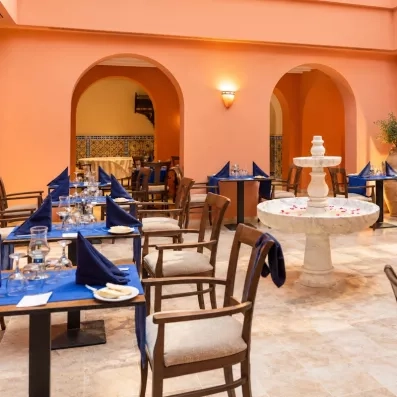 Une salle voûtée aux tons orangés et sa fontaine en marbre, pour un dîner dans un cadre chaleureux et typique.