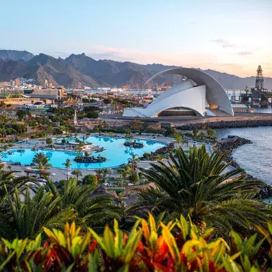 Vue de Santa Cruz de Tenerife au coucher du soleil, auditorium moderne, port, piscines maritimes et montagnes en arrière-plan.
