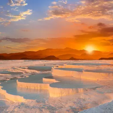 Terrasses blanches de Pamukkale et bassins naturels au coucher du soleil, site géologique spectaculaire à visiter en Turquie.