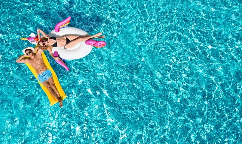 Couple dans une piscine allongé sur des bouées