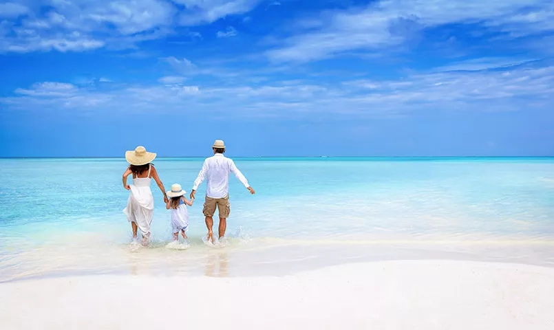 Parents et enfant marchant dans de l'eau bleu de la mer