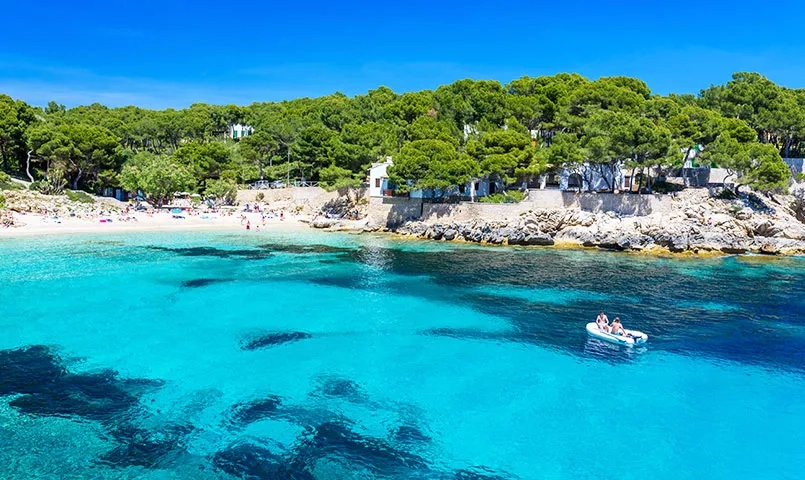 Crique avec eau turquoise et bateau.