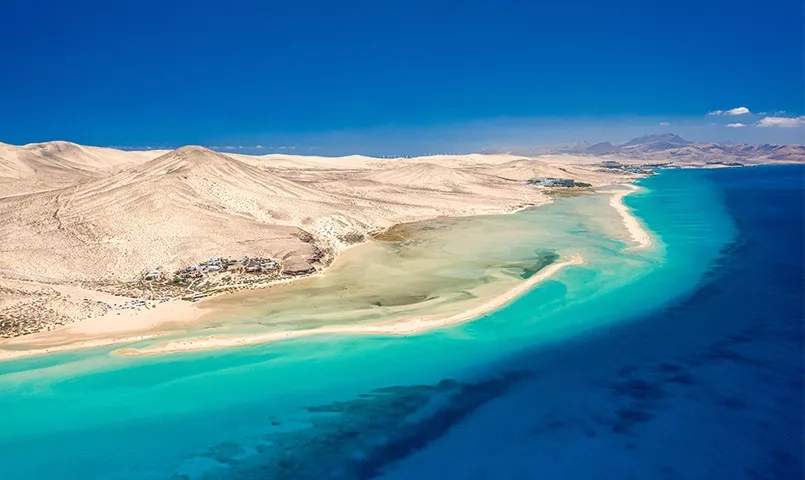 une longue plage de sable devant une mer turquoise