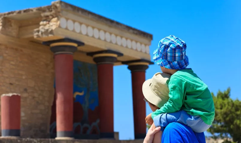 Un papa portant son fils sur ses épaules devant un monument historique. 
