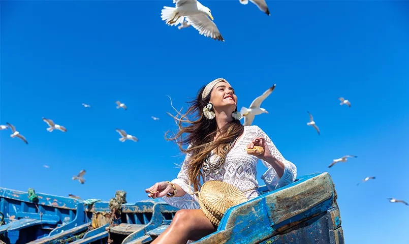 Une jeune femme assise dans un bateau, entourée des mouettes.