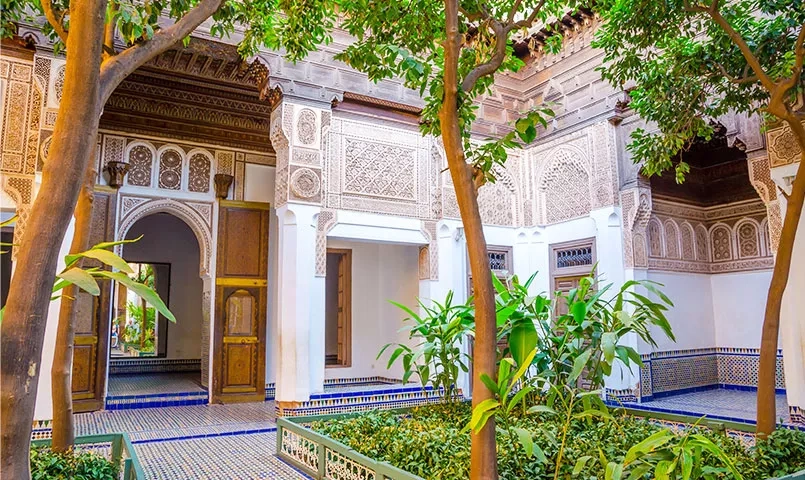 Une cour intérieure marocaine ornée de motifs géométriques et d'un jardin luxuriant. 