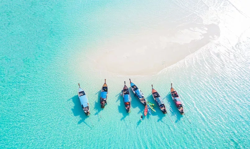 Vue aérienne de bateaux flottant sur une eau turquoise.
