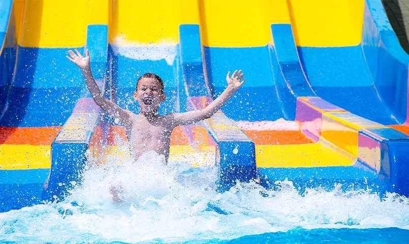 Un enfant joyeux glisse sur un toboggan aquatique coloré. 