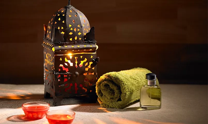 une lampe marocaine en fer forgé, des bougies et une serviette