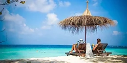 Couple sous un parasol sur des transat au bord de la mer