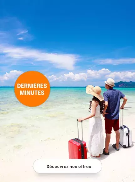 un couple sur une plage avec des chapeaux et des valises à roulettes, prêt à partir en vacances de dernière minute