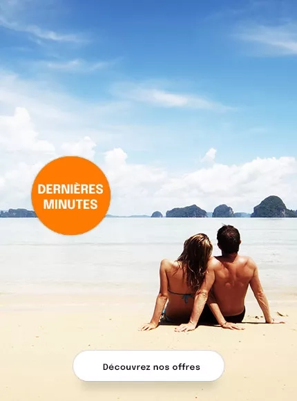 un couple assis sur la plage face à la mer