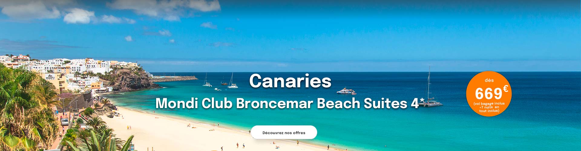 une plage de sable blanc, avec en fond un village de maisons blanches, une mer turquoise avec quelques bateaux