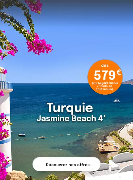 un village de maisons blanches surplombant la mer Egee en Turquie et des bougainvilliers roses en premier plan